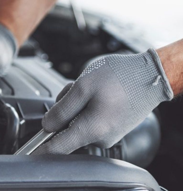 Monteur van F&M Autoservice controleert een onderdeel onder de motorkap