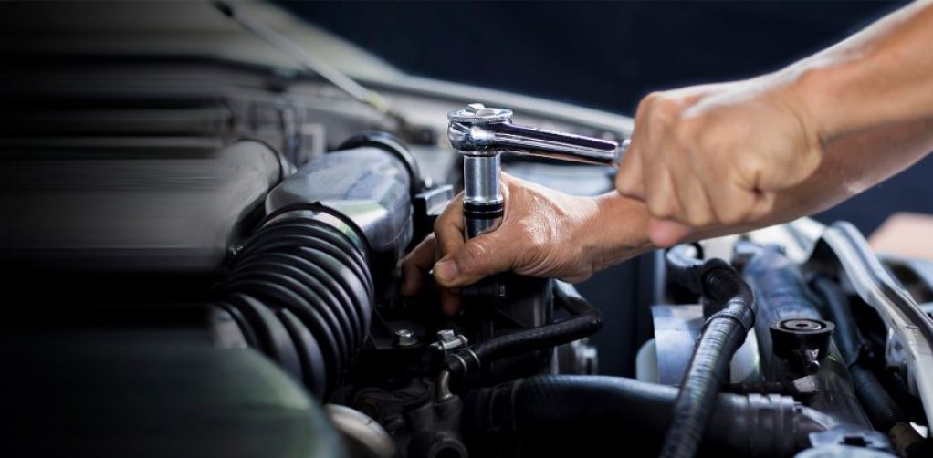 Detailopname van een monteur bij F&M Autoservice in Hazerswoude-Dorp die een dopsleutel met ratel gebruikt op een automotor in een garageomgeving.