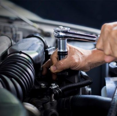 Detailopname van een monteur bij F&M Autoservice in Hazerswoude-Dorp die een dopsleutel met ratel gebruikt op een automotor in een garageomgeving.