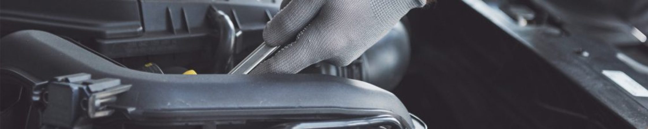 Monteur van F&M Autoservice controleert een onderdeel onder de motorkap