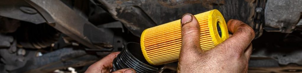 Monteur die, voor onderhoud, een nieuw oliefilterpatroon in de filterbehuizing aan de onderkant van een auto plaatst in de werkplaats van F&M Autoservice.