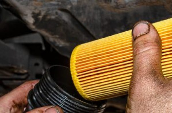 Monteur die, voor onderhoud, een nieuw oliefilterpatroon in de filterbehuizing aan de onderkant van een auto plaatst in de werkplaats van F&M Autoservice.